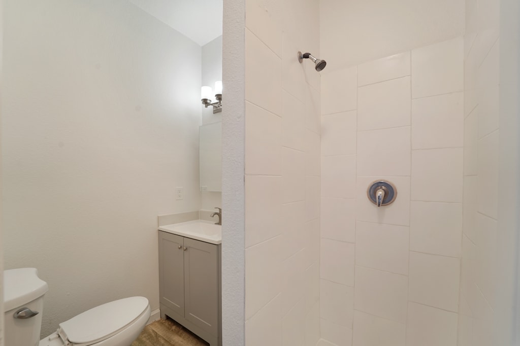 A white bathroom with a toilet, sink, and shower.