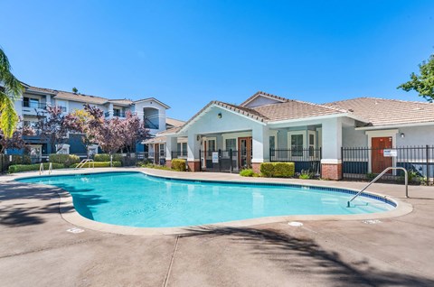 A swimming pool in front of a house with a fence around it.