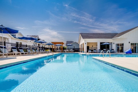 A large swimming pool with a blue tinted water and a white building in the background.