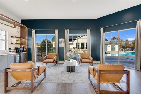 A modern living room with a view of the pool and trees outside the windows.