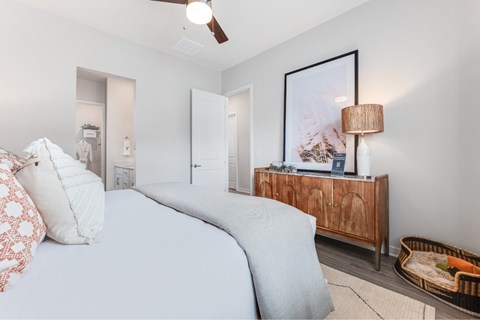 A bedroom with a large bed and a wooden cabinet.