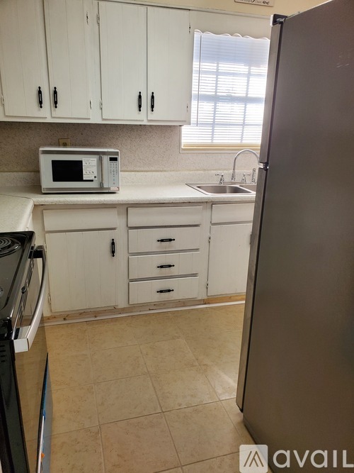 A kitchen with white cabinets and a black refrigerator.