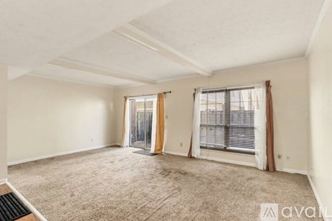 A spacious room with carpeted floor, white walls, and a window with blinds.