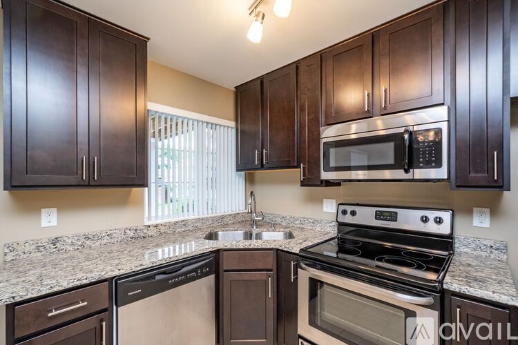 A kitchen with dark brown cabinets and stainless steel appliances.