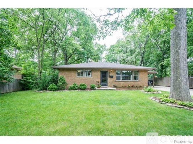 A house with a green lawn and trees in the background.