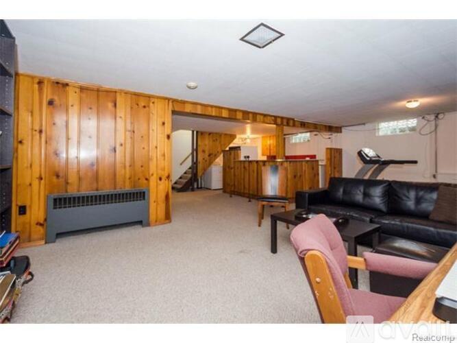 A living room with a black couch and a wooden chair.