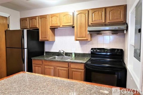 A kitchen with wooden cabinets and black appliances.