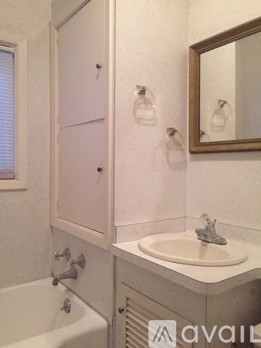 A bathroom with a tub, sink, and mirror.