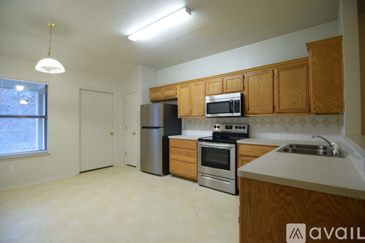 A kitchen with wooden cabinets and stainless steel appliances is available for rent.