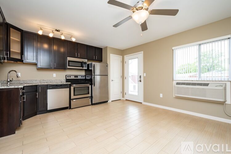 A kitchen with black cabinets and a stainless steel refrigerator.