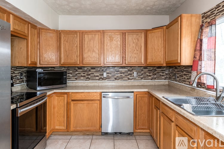 A kitchen with wooden cabinets and a stainless steel dishwasher.