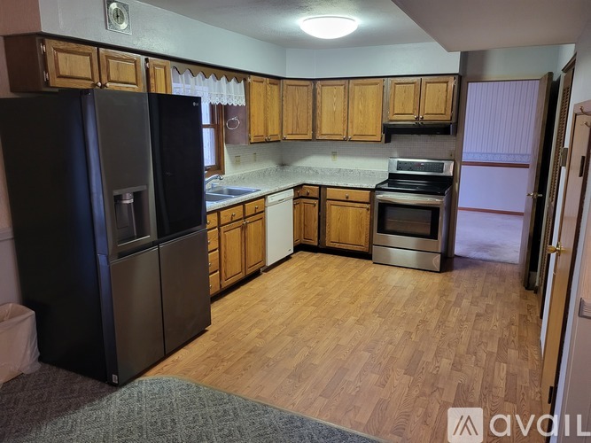 A kitchen with wooden cabinets and a black fridge.