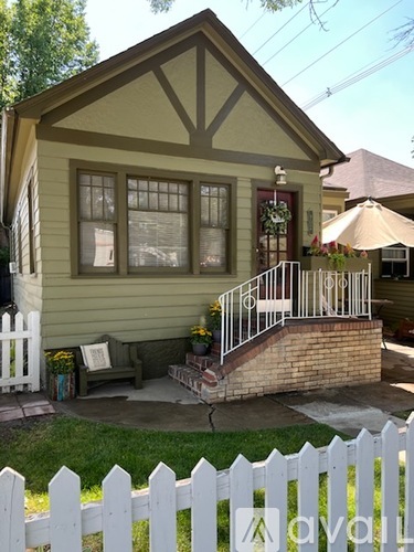 A house with a green front yard and a blue trash can.