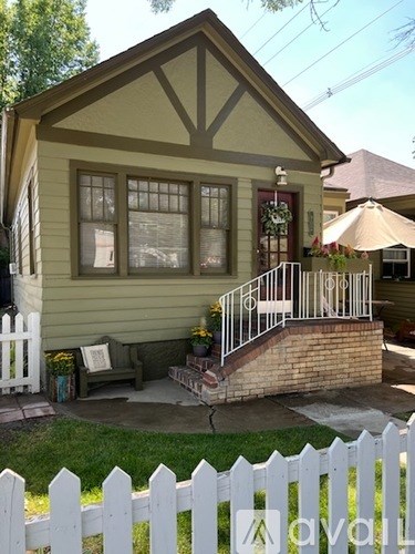 A house with a green front yard and a blue trash can.