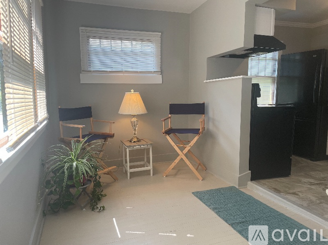 A living room with a black refrigerator and a small table with a lamp on it.