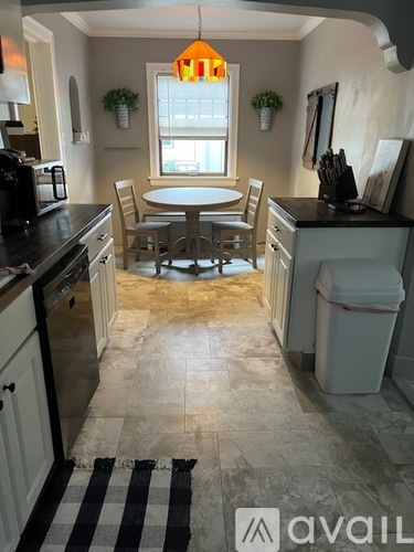 A dining room with a round table and two chairs.
