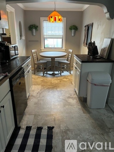 A dining room with a round table and two chairs.