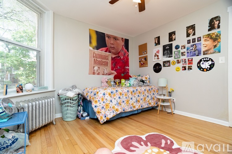 A bedroom with a bed, a poster, and a fan.