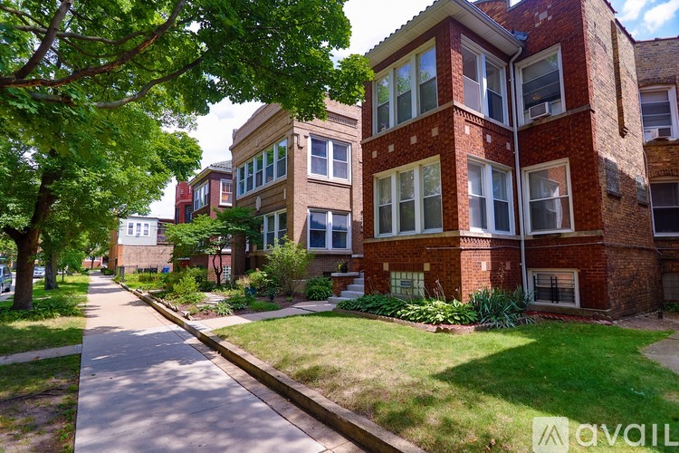 A row of red brick apartment buildings with green trees in front.