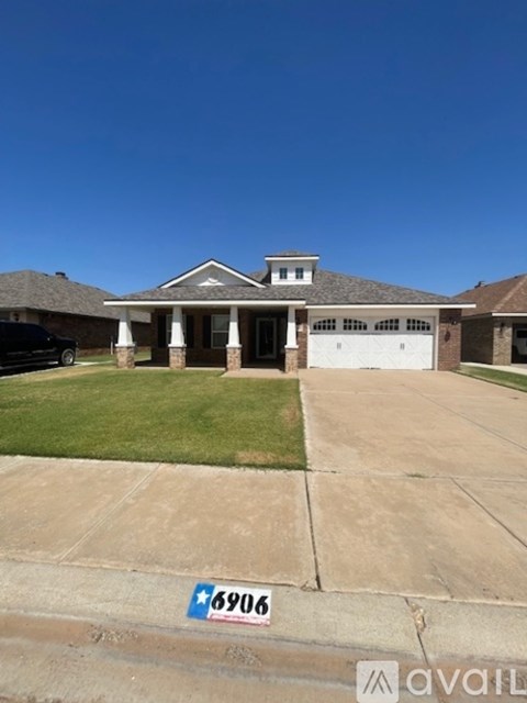 A house with a black car parked in front and a blue and white sign on the ground.