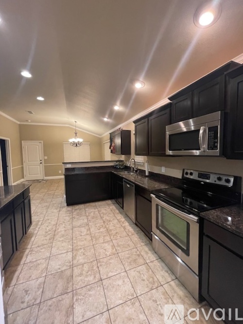 A kitchen with black cabinets and a stainless steel microwave.