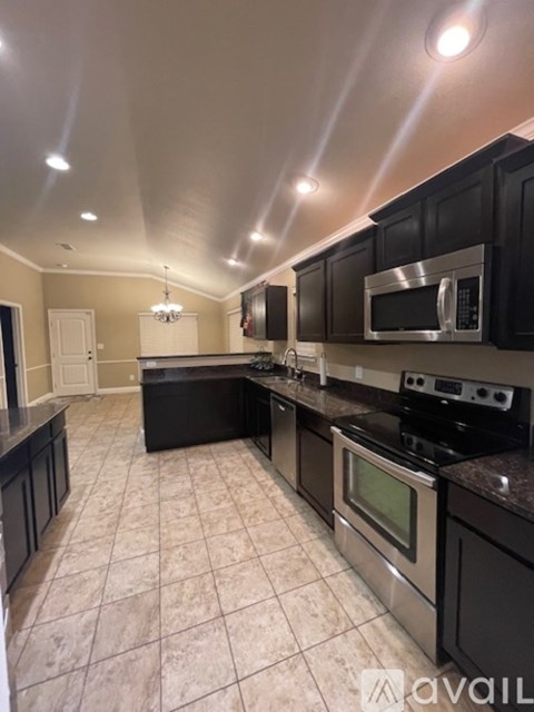 A kitchen with black cabinets and a stainless steel microwave.