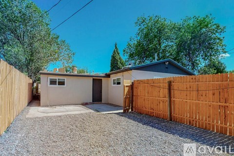 A house with a brown fence and a gravel driveway.