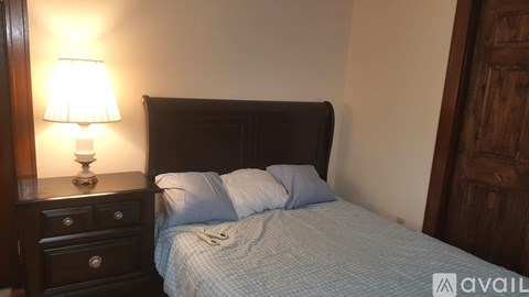 A bedroom with a bed, nightstand, and lamp.