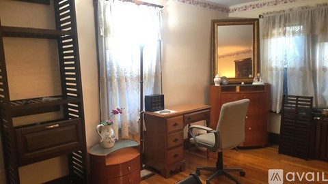 A room with a desk, chair, and a mirror.