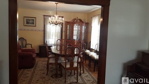 A dining room with a chandelier, a table with chairs, and a framed picture on the wall.