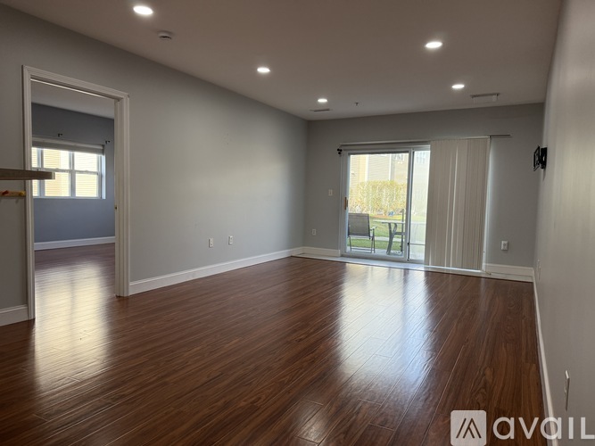 A spacious room with wooden flooring and sliding glass doors.