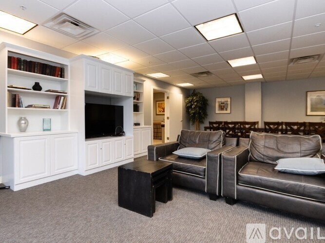 A living room with a grey couch, a black coffee table, and a white entertainment center with a television.