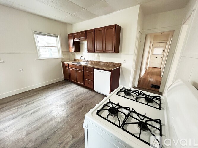 A kitchen with a white gas stove and wooden cabinets.