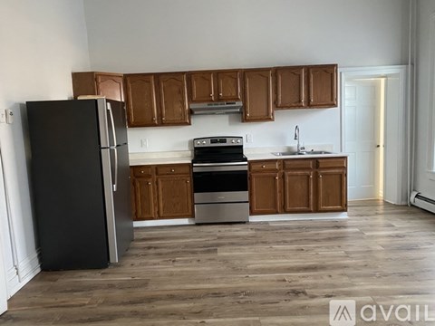 A kitchen with wooden cabinets and a black refrigerator.