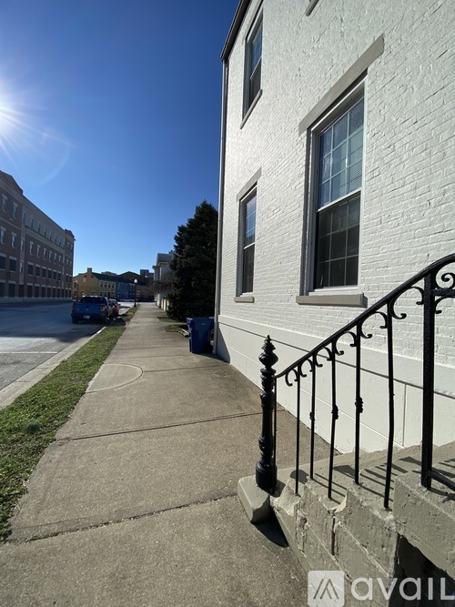 A sunny day on a city street with a white building on the right.