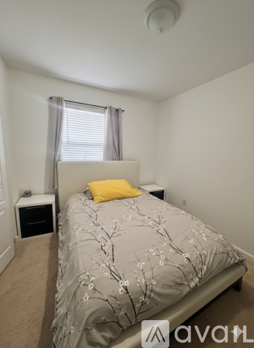 A bedroom with a bed, nightstand, and window with curtains.