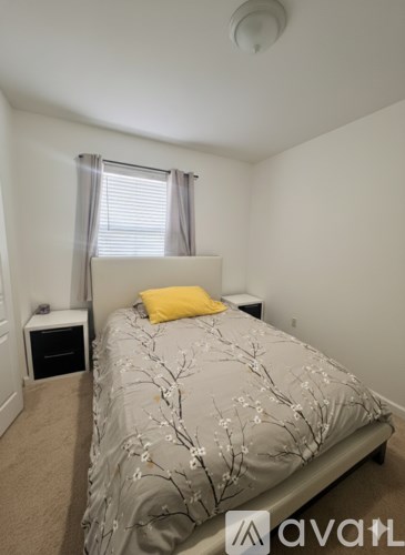 A bedroom with a bed, nightstand, and window with curtains.
