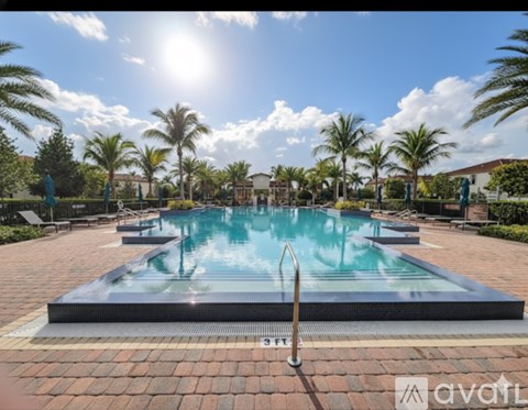 A pool surrounded by palm trees and a sunny sky.