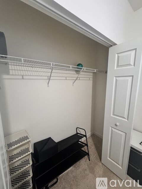 A small room with a shelf, a black bench, and a door.