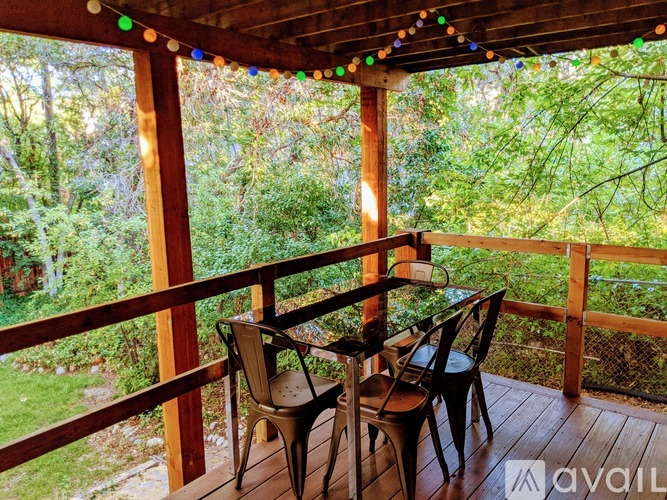 A wooden deck with a table and chairs and string lights.