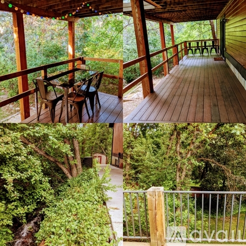 A wooden deck with a table and chairs overlooking a lush green forest.