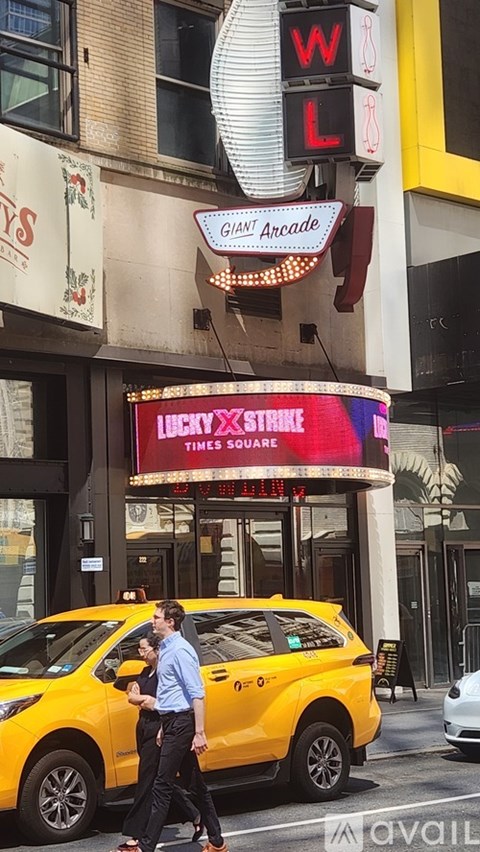 A yellow taxi is parked in front of a building with a sign that reads "Clint Acadde.".