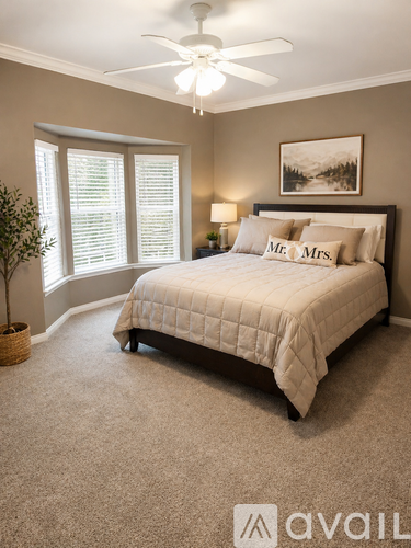 A bedroom with a bed, a ceiling fan, and a window with blinds.