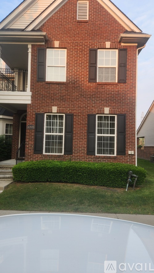 A red brick house with black shutters and a white window.