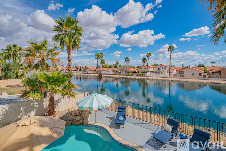 A pool area with a blue umbrella and a pool with a slide.