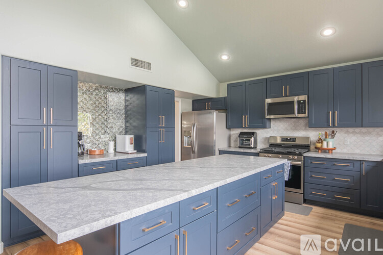 A kitchen with blue cabinets and a marble countertop.
