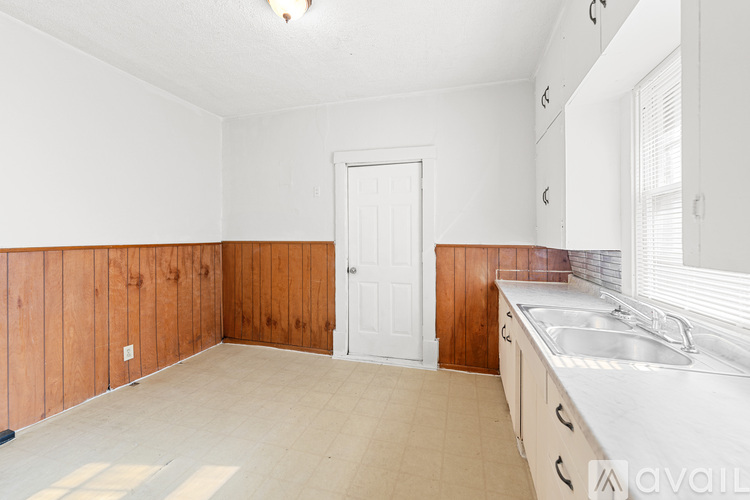 A kitchen with wooden walls and a white door.