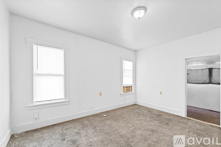 A spacious empty room with a window and a carpeted floor.