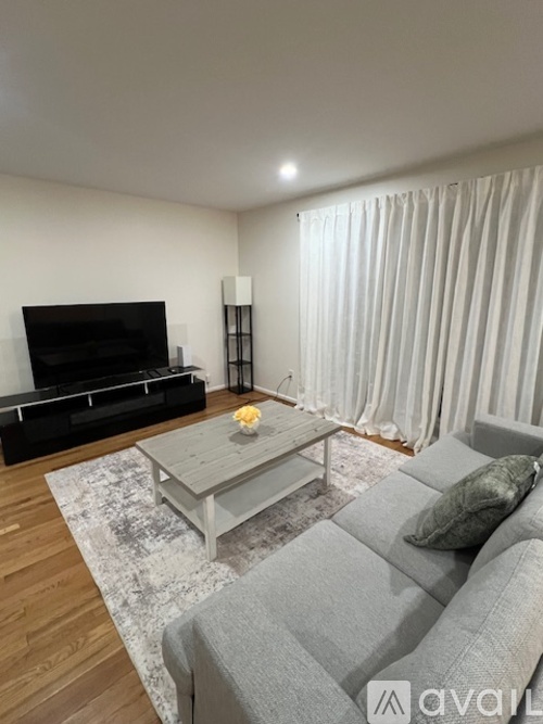 A living room with a grey sofa, a wooden coffee table, and a black television.