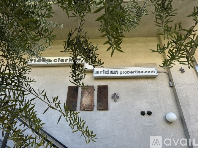 A wall with a sign that says "Aridan properties.com" and a window with a metal grate.
